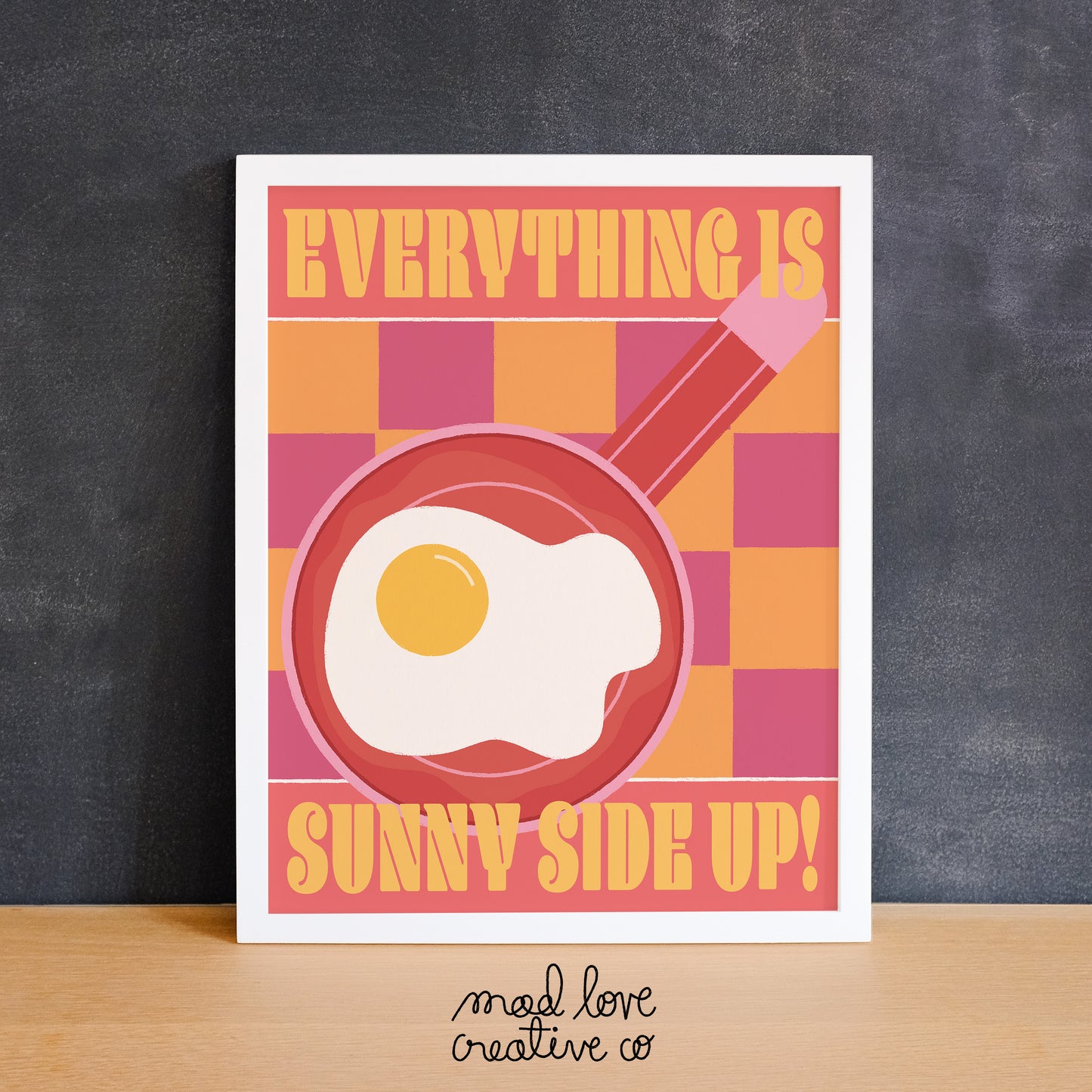 Bright colored checkered print with a sunny side up egg on a frying pan with the text "everything is sunny side up". Made in Canada by Mad Love Creative Co.