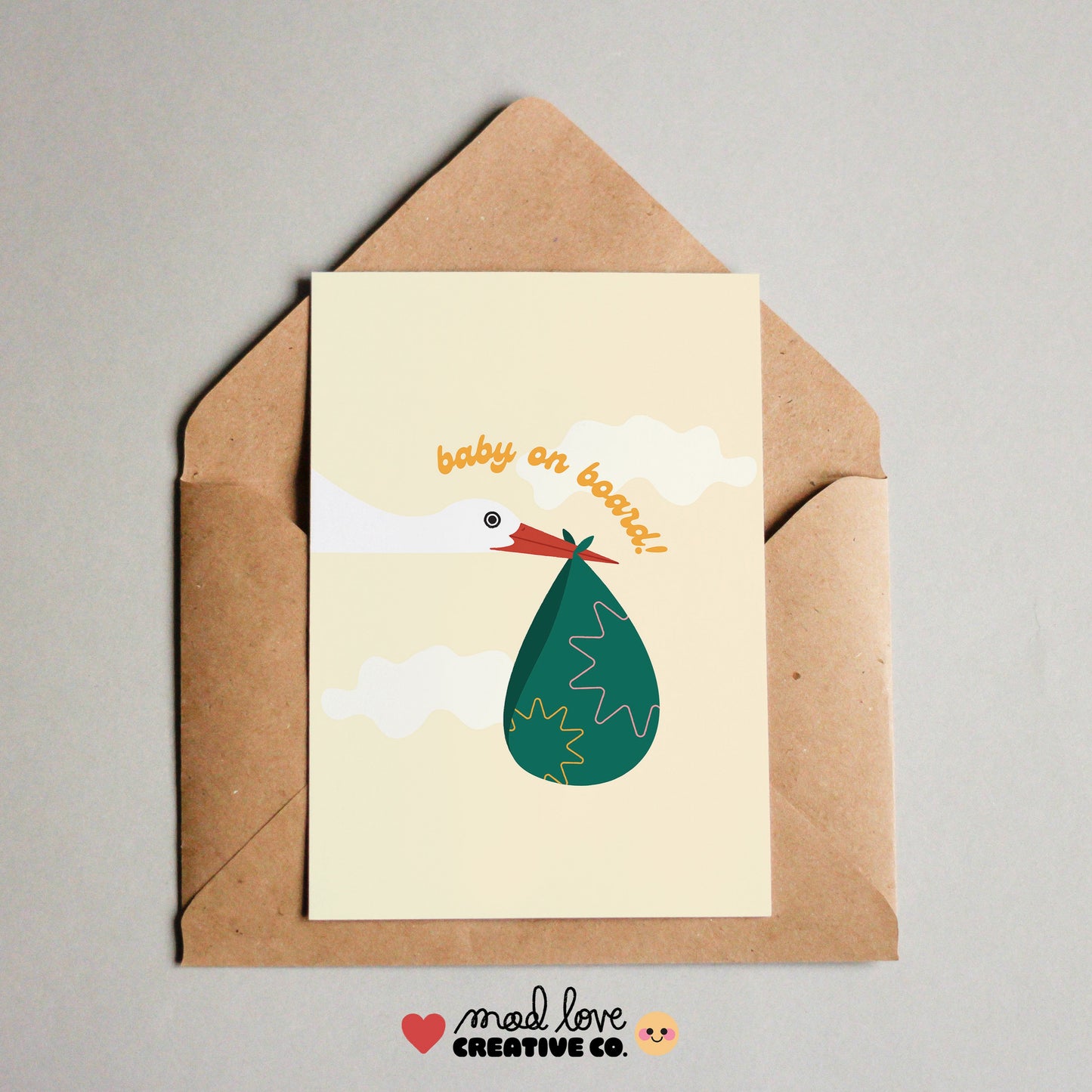 Cute card featuring a stork carrying a parcel with the phrase "baby on board". Made in Canada by Mad Love Creative Co.
