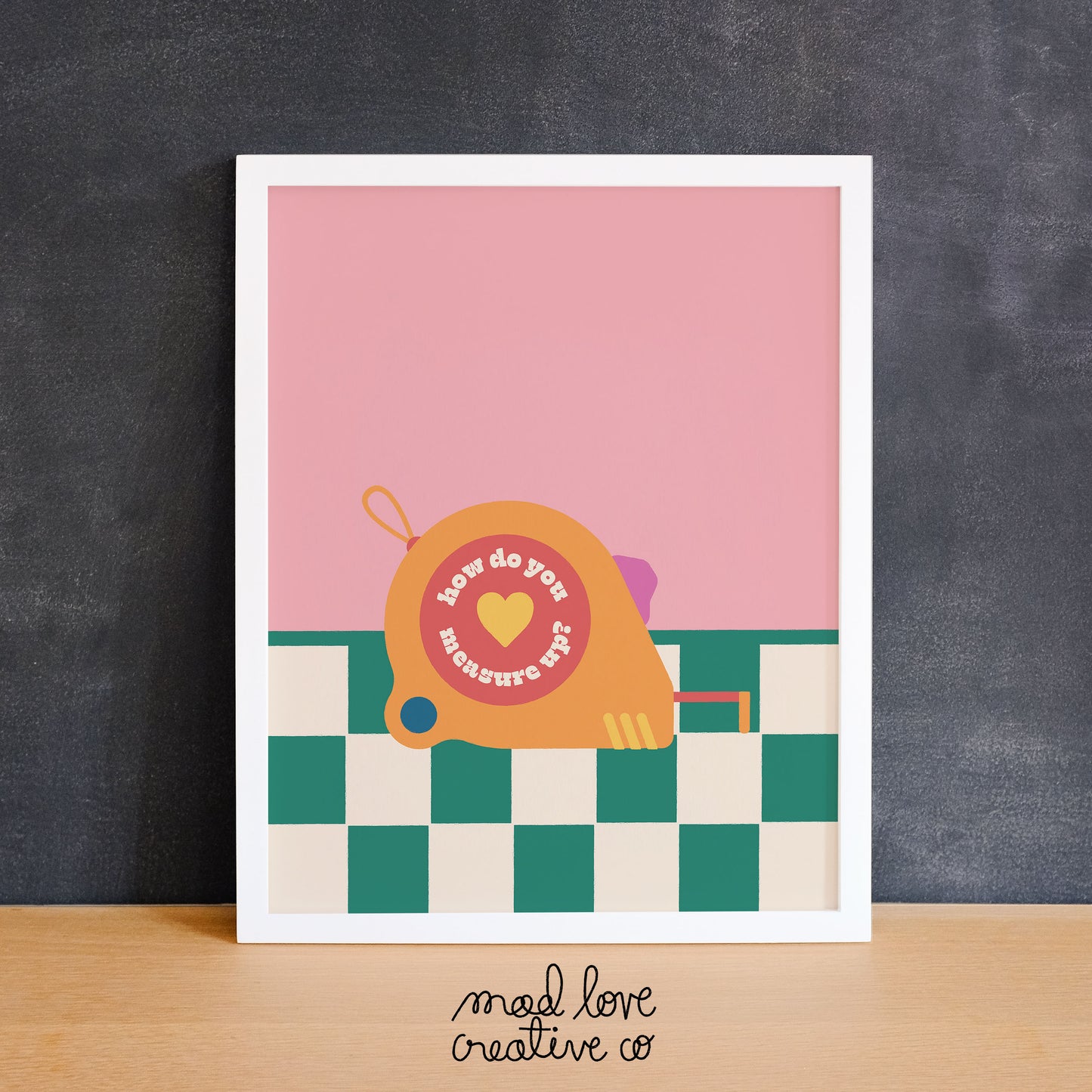 Bright coloured print of a measuring tape on a green checkered floor with the phrase "how do you measure up". Made in Canada by Mad Love Creative Co.
