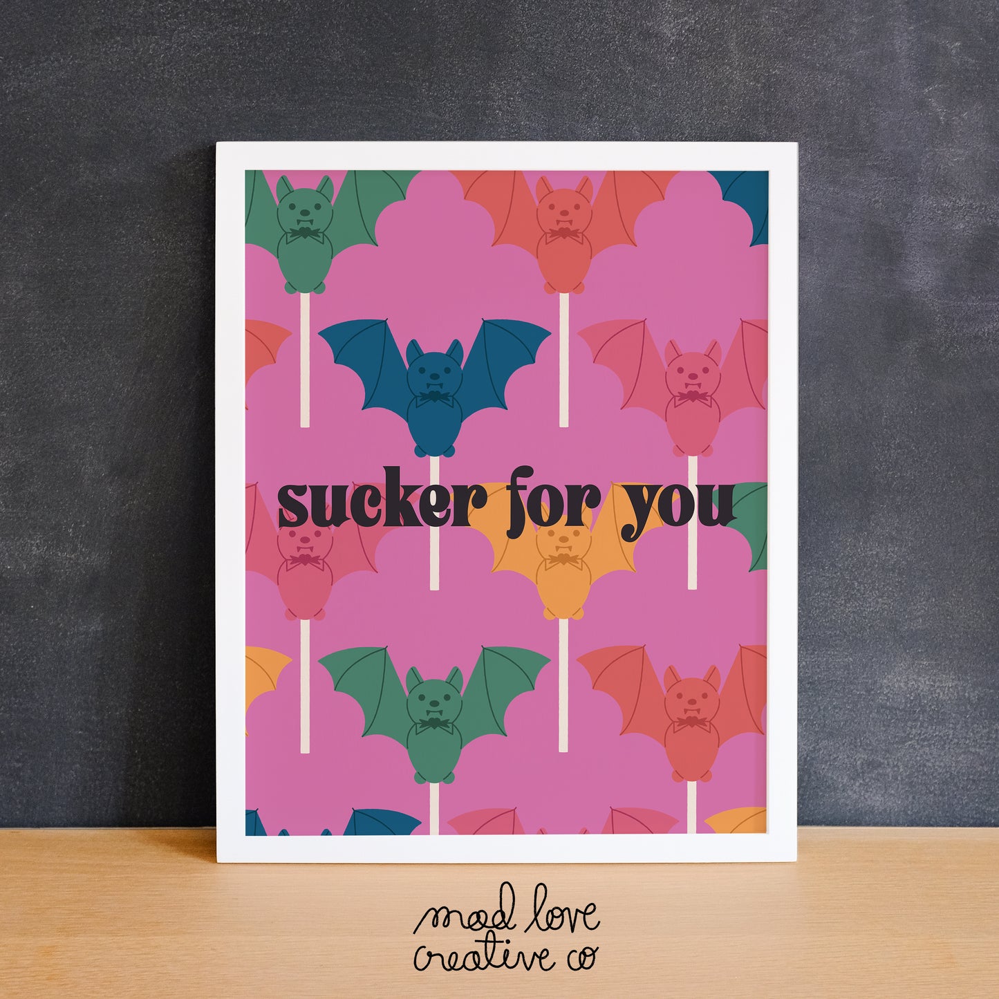 Colourful print of a pattern of bat lollipops with the text "sucker for you". Made in Canada by Mad Love Creative Co.