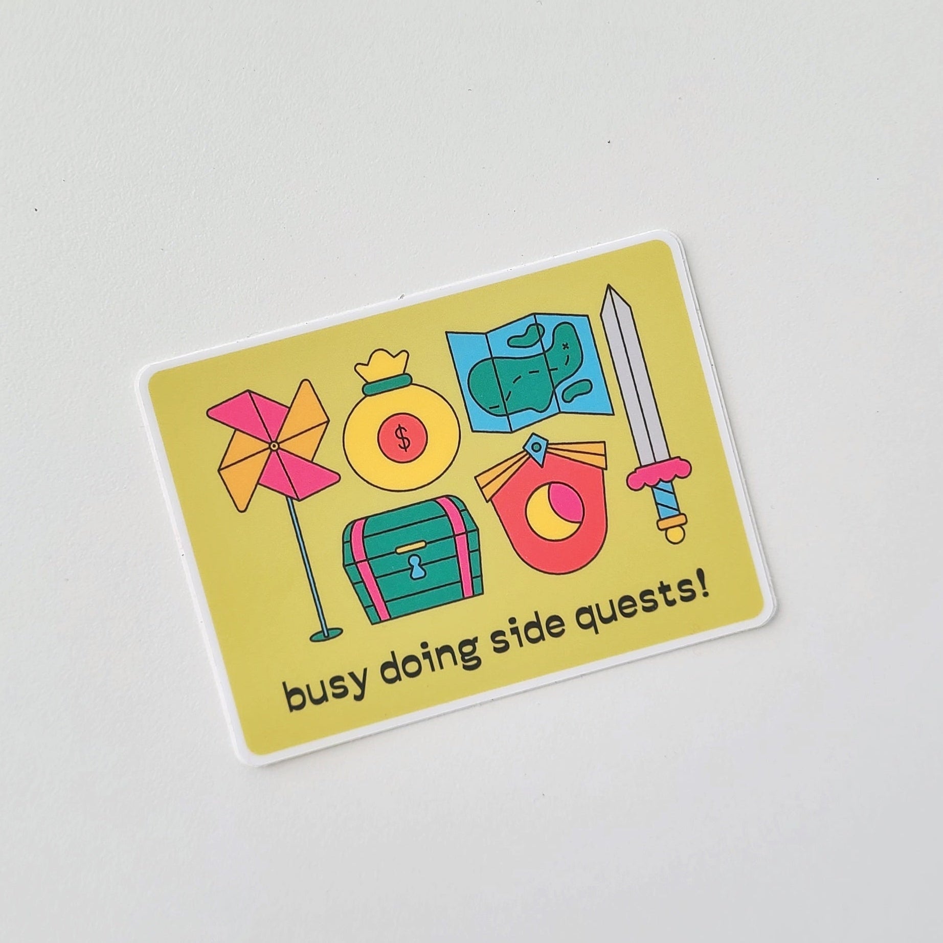 Sticker with colorful icons and text 'busy doing side quests!' on a light gray background