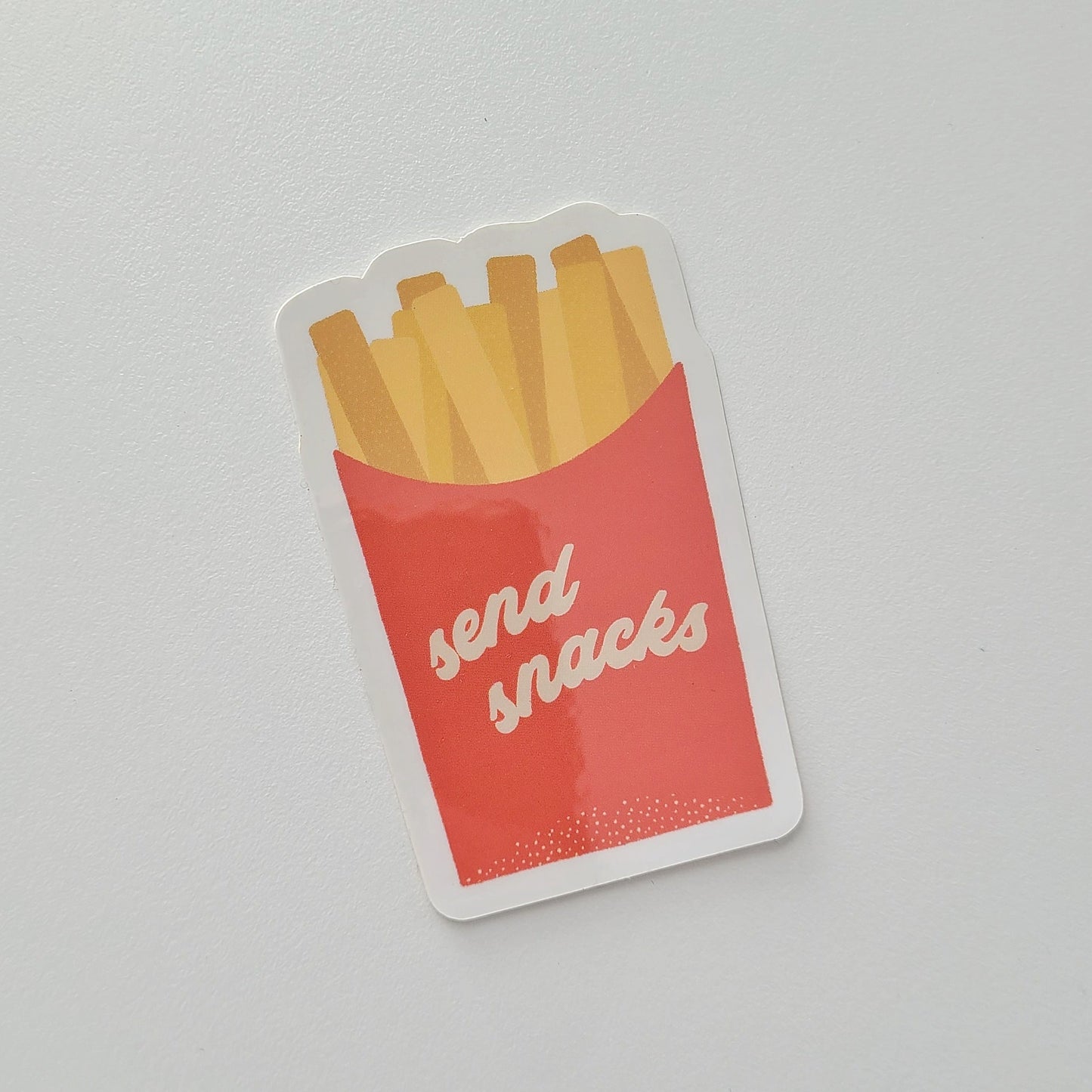 Sticker of a red box of fries with 'send snacks' text on a gray background