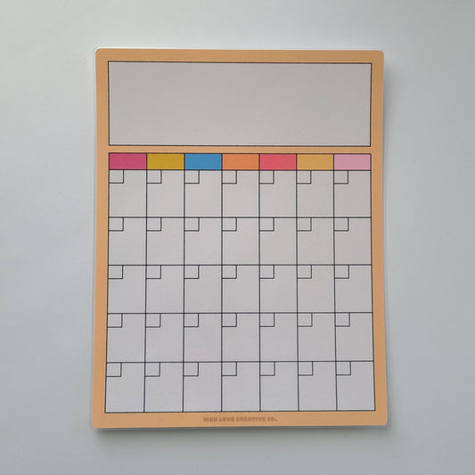Dry erase calendar with color-coded markers on a light gray wall