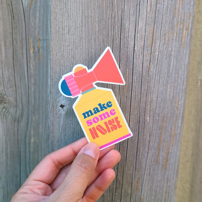 Vinyl sticker shaped like an air horn with the quote "make some noise". Made in Canada by Mad Love Creative Co. 